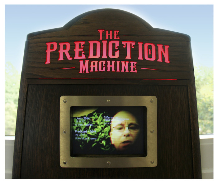 the screen with a face on it and the sign with blue skies and trees in the background