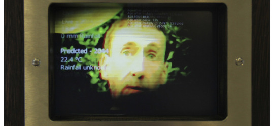 a face and weather data appearing on the screen