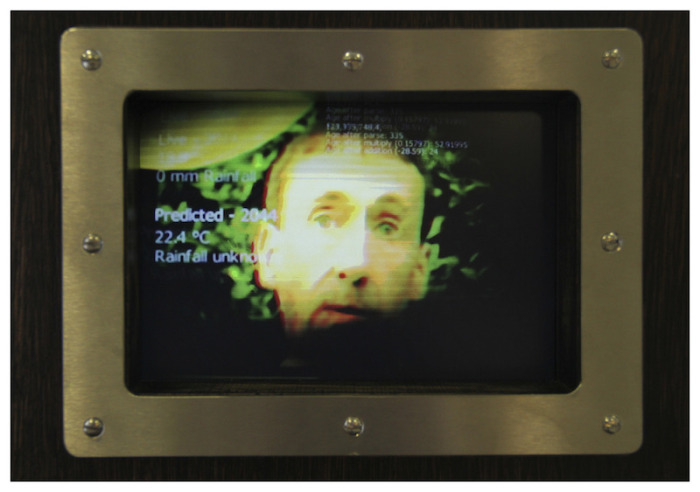 a face and weather data appearing on the screen