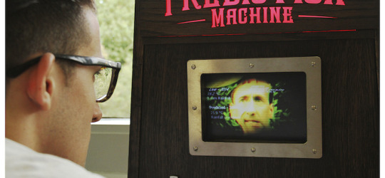 a man looking at the screen and lit up sign of The Prediction Machine