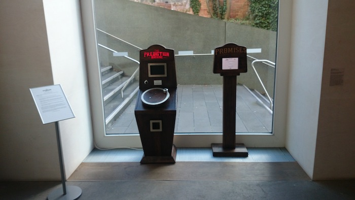 The Prediction Machine and the Promises and Wishes Machine installed in the window with a stand with instructions and